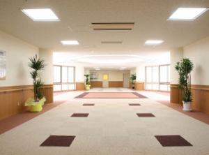 広々とした共用スペース。天井照明が明るく、観葉植物が配置された落ち着きのある空間